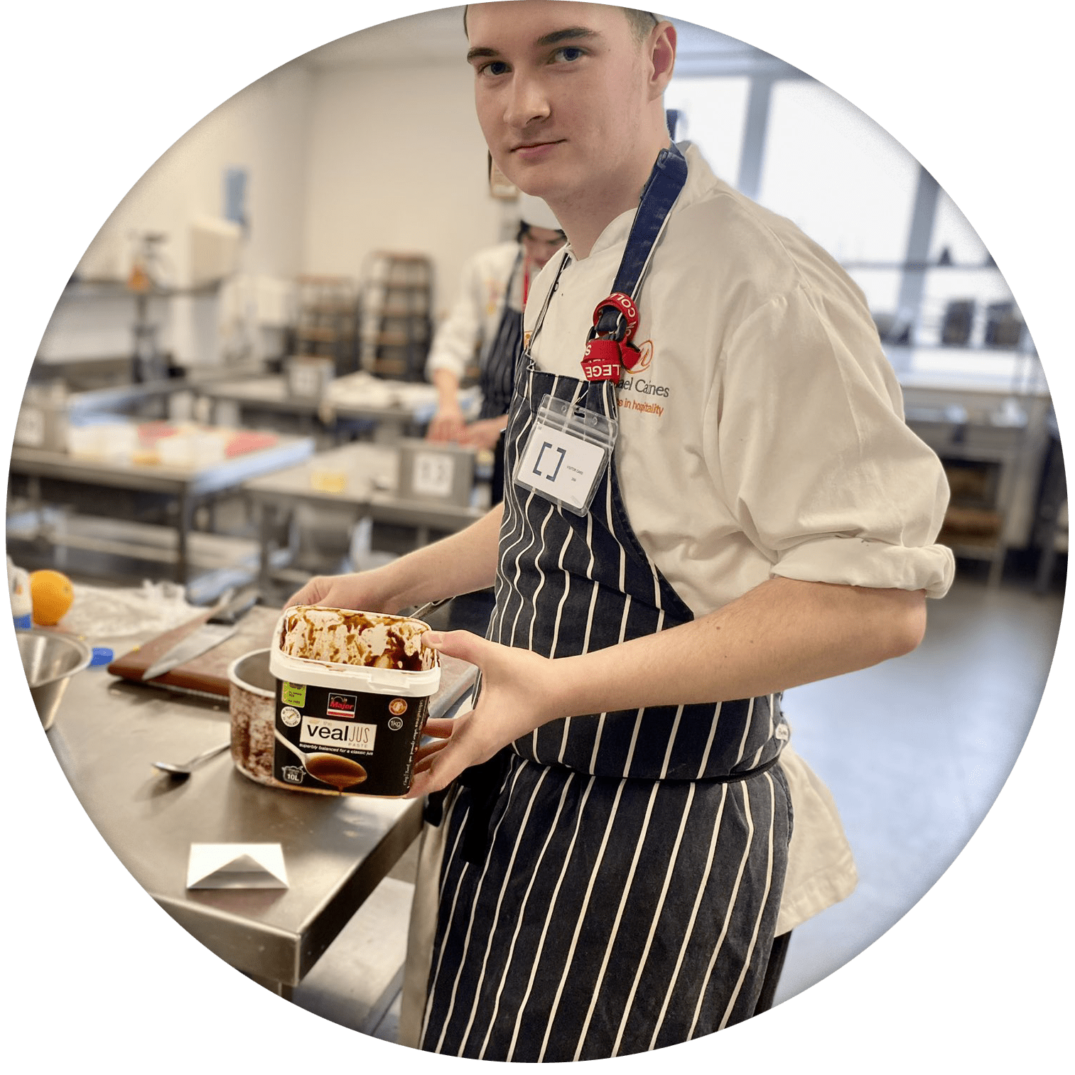 young male chef in kitchen holding jus
