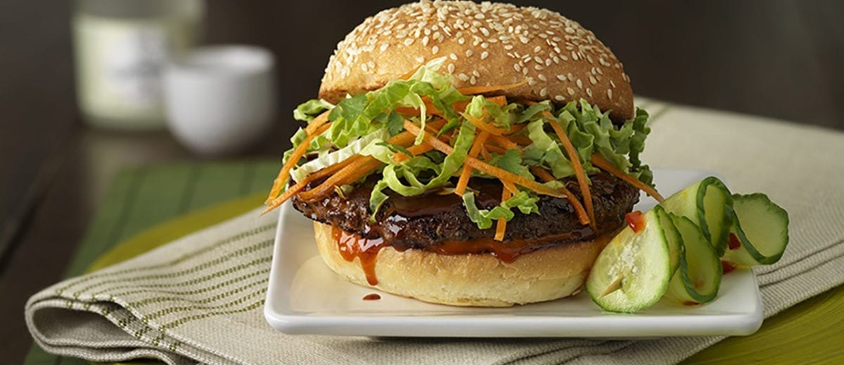 burger on seeded bun with lettuce and shaved carrots, cucumbers on the site