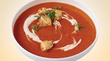 red pepper soup in a bowl with garnish