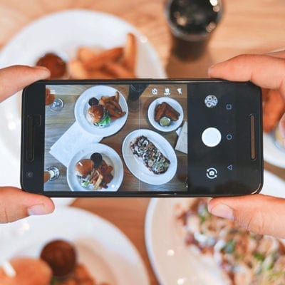 person holding smart phone taking photo of food