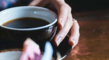 hands holding mug with black coffee