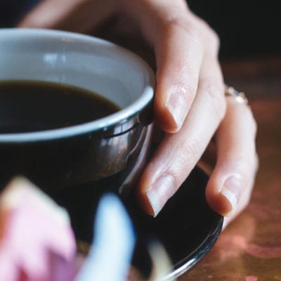 hands holding mug with black coffee