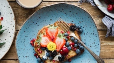 french toast and berries on colorful speckled plates