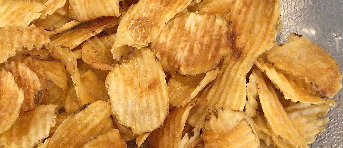 fresh fried crinkle chips on a black plate with dipping sauce