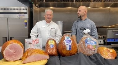 two men behind ham display