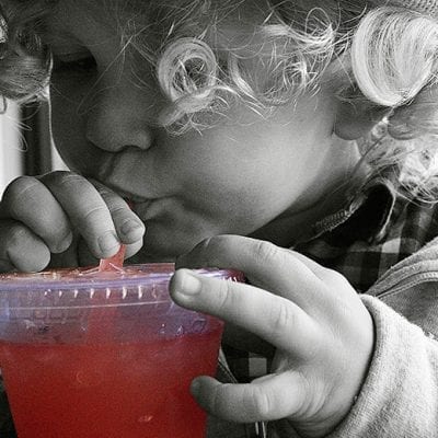 child sipping drink straw clear cup