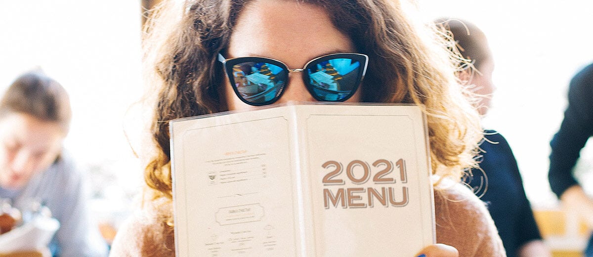 woman with sunglasses holding 2021 menu in front of face