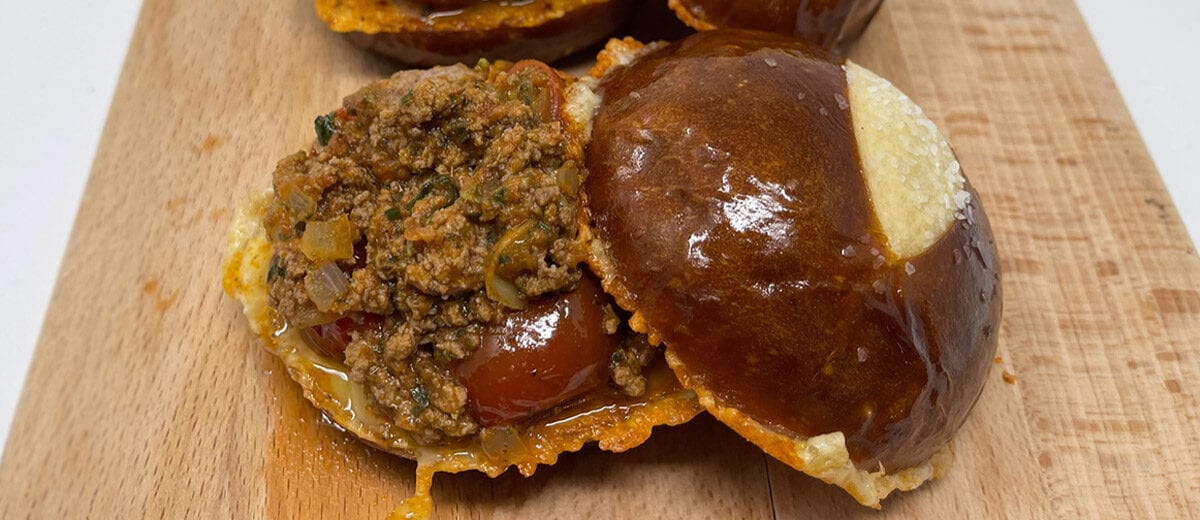 sloppy joe sanwiches on pretzel buns, on cutting board