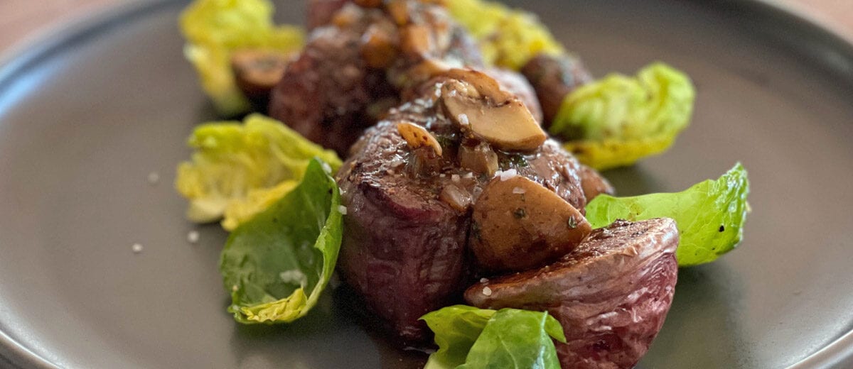 beef medalions with Brussels sprout leaves and mushrooms