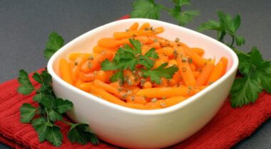 seasoned slim baby carrots in a white bowl placed on a grey countertop