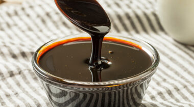 Dark molasses in a glass bowl on tablecloth