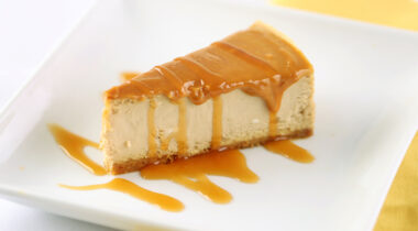 Silce of salted caramel cheesecake on a white plate with a caramel drizzle