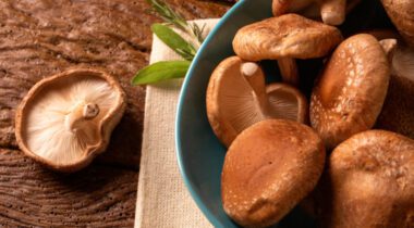 Shitake mushrooms in a blue bowl on wooden table