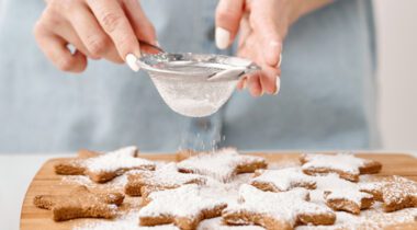 female hands putting powdered sugar on star shaped cookies
