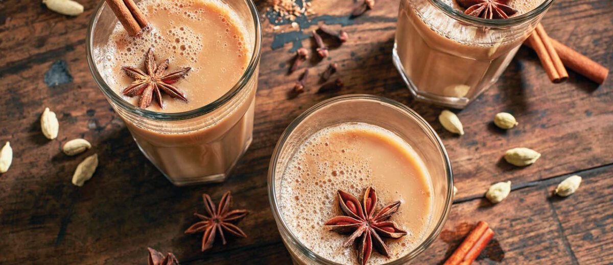 three glasses filled with hot vanilla chai and cinnamon sticks and star shaped vanilla spice