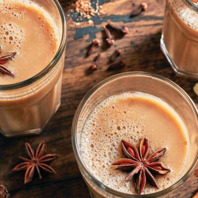 three glasses filled with hot vanilla chai and cinnamon sticks and star shaped vanilla spice