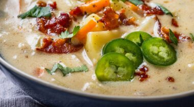Creamy soup with bacon potatoes cheese jalapeños in a blue bowl on table