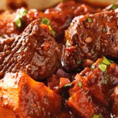 bowl of beef stew with big chunks of beef, sweet potato and spices