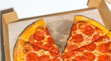 pepperoni pizza on liner in box with one slice missing