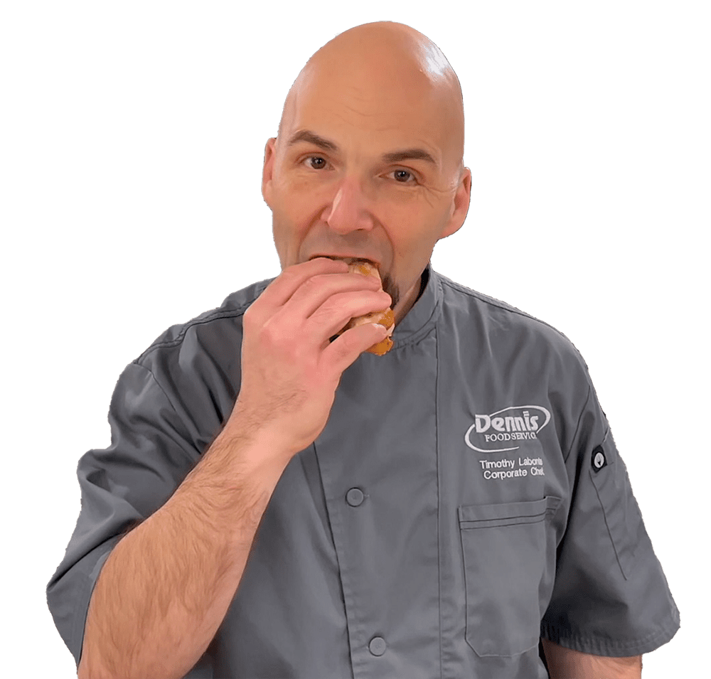 bald chef in gray shirt biting a sandwich