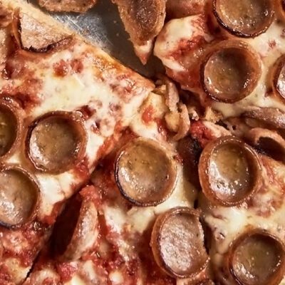 cooked cupped sausage slices on a pizza