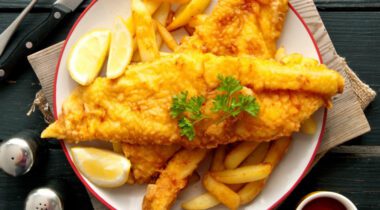 fried fish on plate of fries with lemon