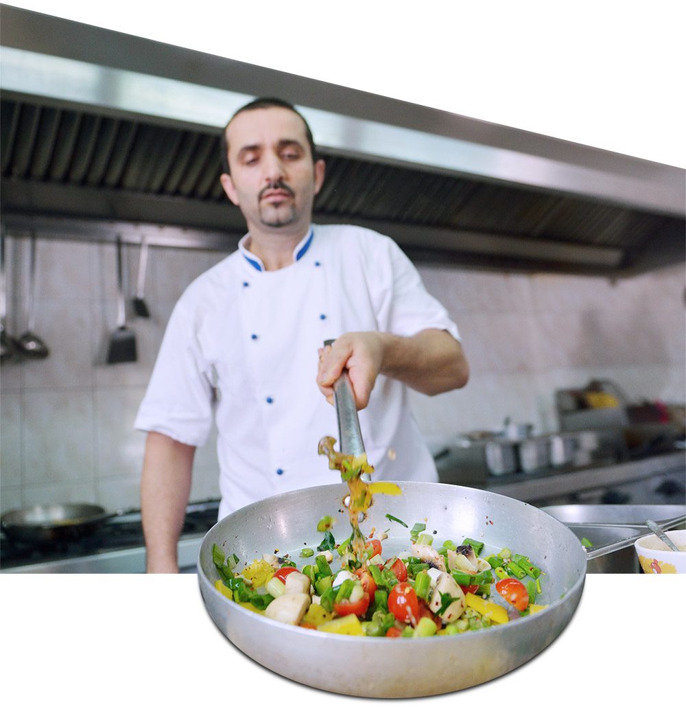 chef sauteing vegetables in a frying pan wok