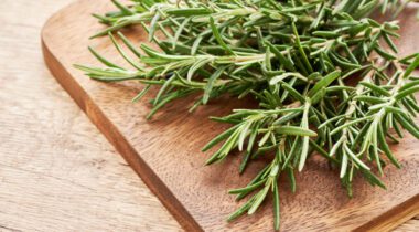 rosemary on wood cutting board on wooden table background