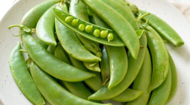 pile of sugar snap peas on white plate