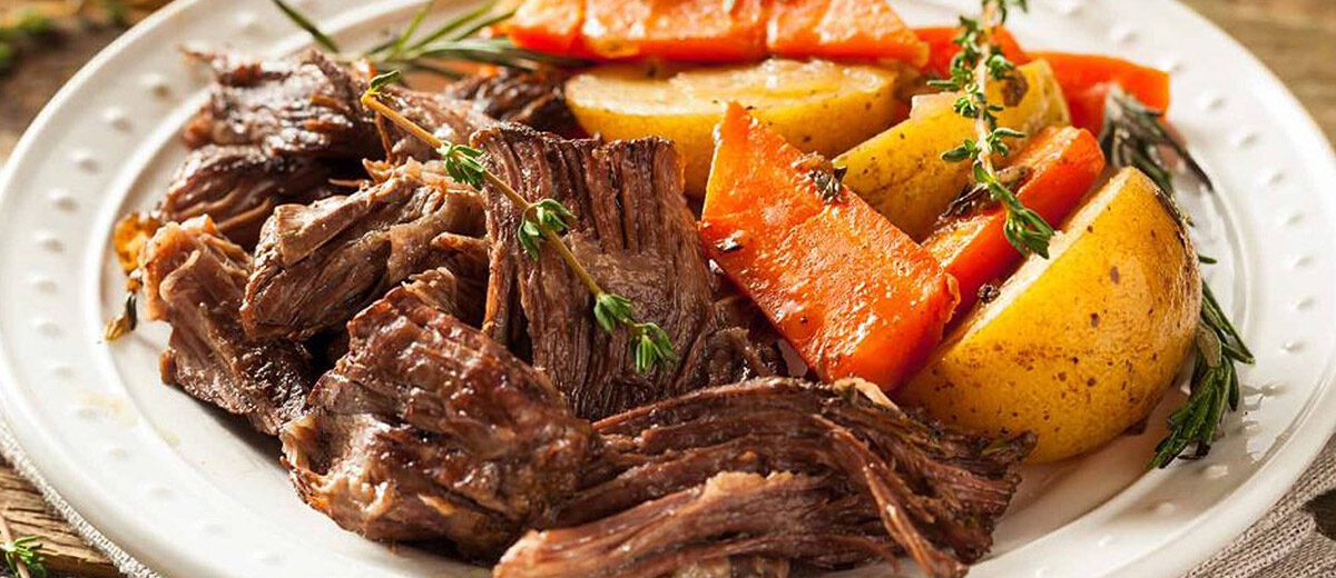 plated pot roast dinner, shows shredded beef with side of root vegetables