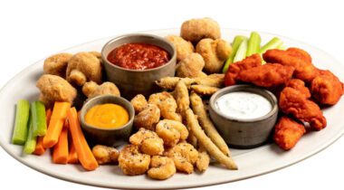 white platter with breaded mushrooms, shrimp, chicken pieces, three different dips and vegetables, ready to be served