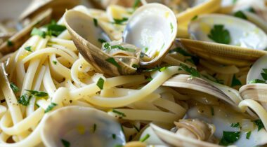 cooked clams and herbs on a plate with linguini noodles