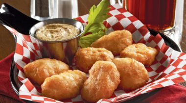 7 cooked battered chicken wings in serving platter with ground mustard dipping sauce.