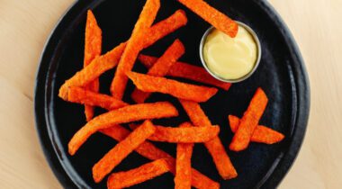 black plate with cooked sweet potato fires and dip