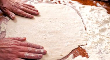 pizza dough on tabletop with flour