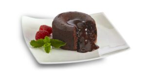 chocolate lava cake cut on white plate with mint leaf and 2 raspberries