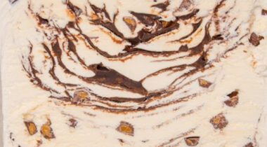 close up of vanilla ice cream with chocolate and peanut butter cups swirled in, aka moosetracks ice cream