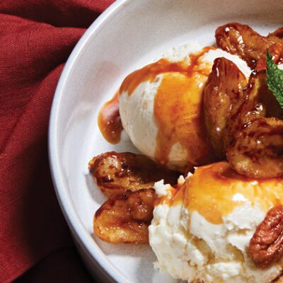 White bowl with Horchata Bites covered in caramel sauce, walnuts, bananas and ice cream