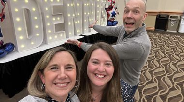 almost bald man and two women smiling at camera