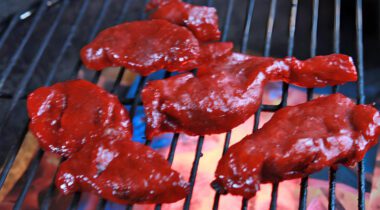 pink chinese-style sauced pork chunks on a bbq grill