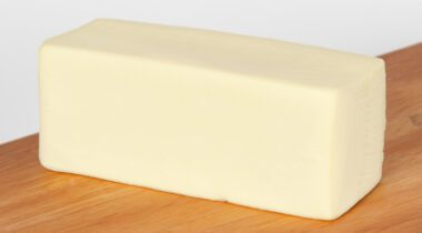 large block of mozzarella cheese on wood cutting board