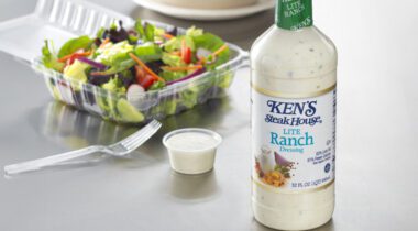 bottle of Ken's Lite Ranch Dressing on tabletop with plastic container of salad in background
