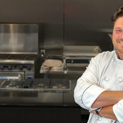 male chef standing in kitchen with arms crossed