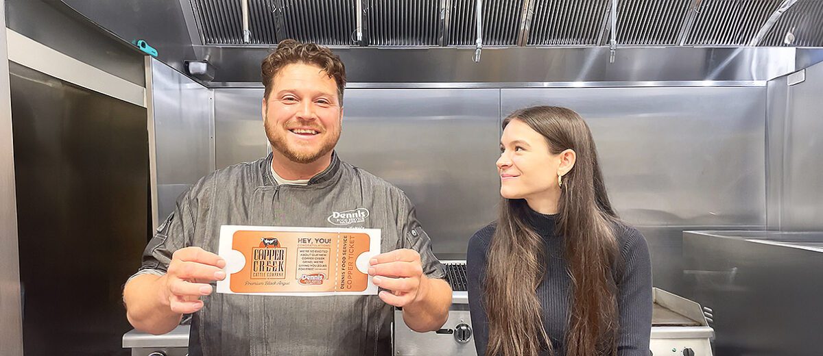 man holds a paper up in a kitchen while woman looks on