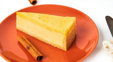 one slice of pumpkin cheesecake on orange plate.