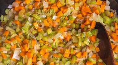 a cast iron skillet, cooking diced carrots, onions, and celery