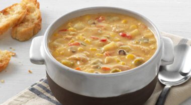 a bowl of chicken and corn chowder, spoon, crusty bread