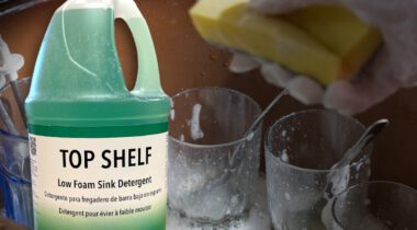 Gallon jug of Top Shelf Detergent over glass cups in sink