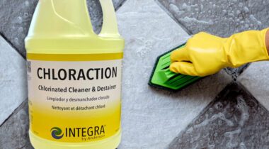 Gallon jug of Chloraction Cleaner over gloved person cleaning tile floor