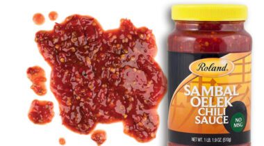 Jar of Sambal Oelek Chili Sauce over textured sample of sauce on white background